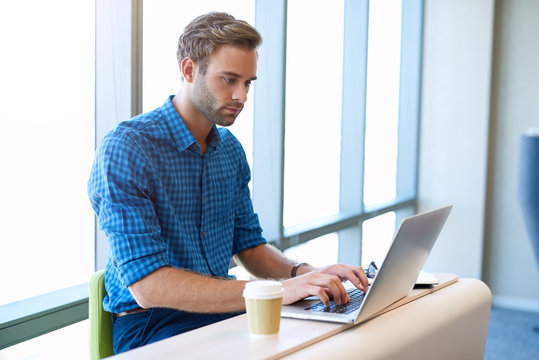 Young Designer Working In Modern Office With Large Windows