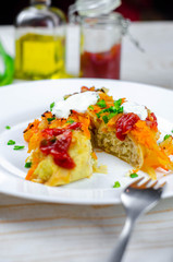 Homemade cabbage rolls with carrots, red tomato sauce and cream on a white plate