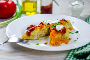 Homemade cabbage rolls with carrots, red tomato sauce and cream on a white plate