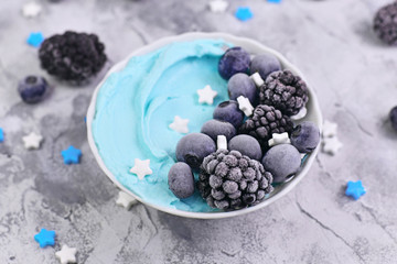 Healthy healthy cegan banana cream fruit smoothie bowl with natural blue spirulina powder topped with blackberry and blueberry fruits