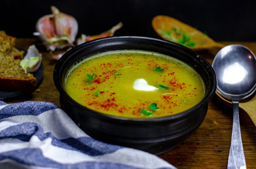 Homemade pea soup with garlic and rustic bread on a dark background