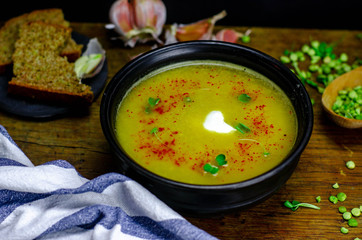Homemade pea soup with garlic and rustic bread on a dark background