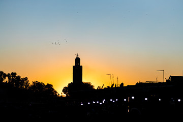 Orange sunset in the tower of the Marrakech square from a square. Morocco..
