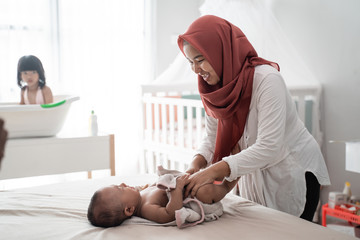 muslim mother applying baby oil to her baby boy after a bath