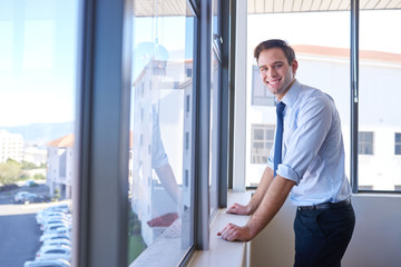 Young businessman smiling in his office with large windows