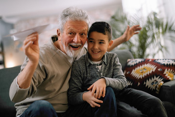 Grandfather teaching his grandson how to make paper airplane. Grandpa and grandchild playing...