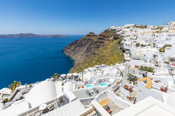  Santorini, Greece. Famous view of traditional white architecture Santorini landscape with flowers in foreground. Summer vacations background. Luxury travel tourism concept. Amazing summer destination