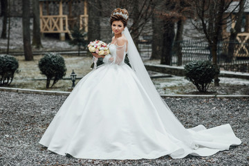 Beautiful bride in white dress in the garden. Beautiful bride perfect style. Wedding hairstyle make-up luxury wedding dress and bride's bouquet. Details for marriage, and for spouses