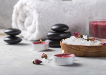 Fototapeta na wymiar Beauty still life sea salt, aroma essential and natural fragrance salt with stones, candles on concrete grey table. Composition of spa treatment