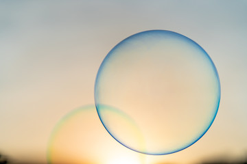 Floating bubbles against sunset scape.