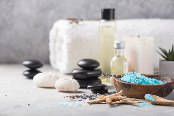 Fototapeta na wymiar Beauty still life of massage oil bottle of aroma essential and natural fragrance salt with stones, candles on concrete grey table. Composition of spa treatment
