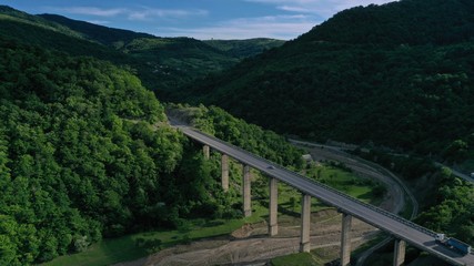 Aerial view of bridge over Aragvi river near Ananuri Fortress and Church. Mountain landscape. Summer. Green trees. Cars going on bridge road. Georgia.