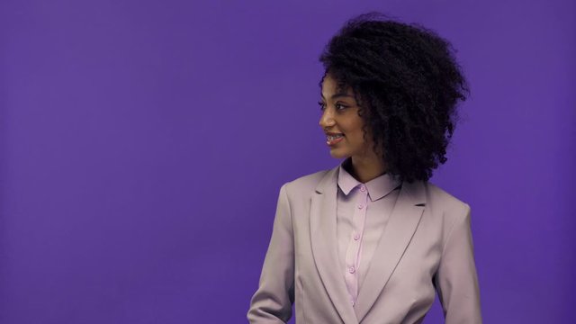 cropped view of woman holding terminal and african american businesswoman paying with credit card isolated on purple 