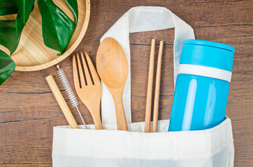 Zero waste concept. Textile eco bags, wooden glass and bamboo utensil on wooden background.