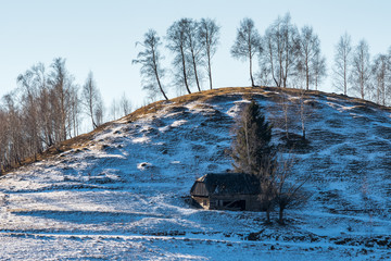 Winter Scenery Created by a Wooden House Standing on a Hill and  a Few Trees above