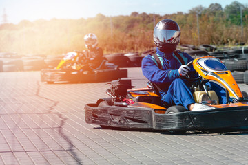 A driver in gear and helmet drives a racing car. In action. Go karts racing, sreet karting, rent. extreme sport. fun entertainment for drivers. Soft light glow, copy space - obrazy, fototapety, plakaty