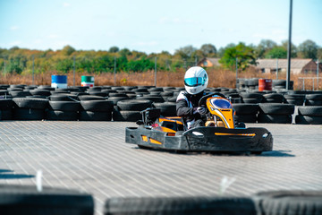 A driver in gear and helmet drives a racing car. In action. Go karts racing, sreet karting, rent. extreme sport. fun entertainment for drivers - obrazy, fototapety, plakaty