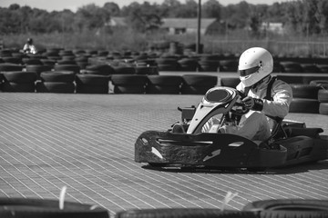 Black and white. A driver in gear and helmet drives a racing car. In action. Go karts racing, sreet karting, rent. extreme sport. fun entertainment for drivers