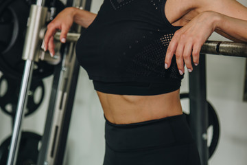 Rear view of a young adult girl doing heavy squats in the gym with a barbell. The concept of...