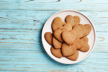 Delicious homemade cookies hearts on a plate on a wooden background. Top view. Place for text.