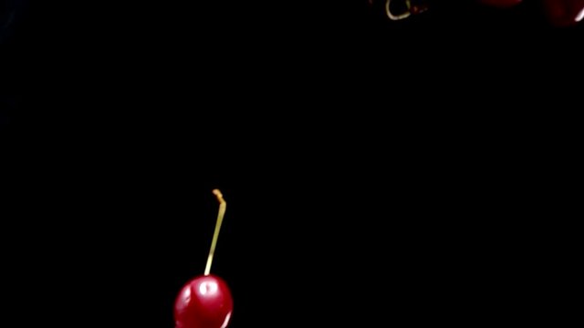 Rpe cherries fly on a black background closeup in slow motion