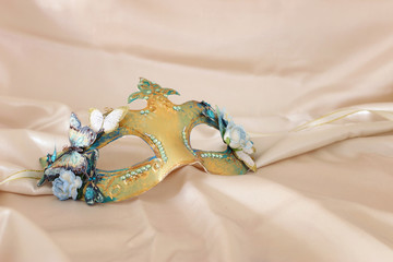 Photo of elegant and delicate gold Venetian mask over white silk background