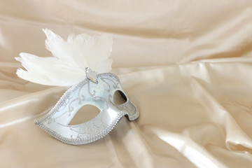 Photo of elegant and delicate white Venetian mask over white silk background