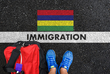 Man in shoes with bag standing next to line with word IMMIGRATION and flag of Mauritius on asphalt...