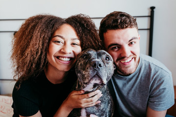 happy couple in love at home. Afro american woman, caucasian man and their pit bull dog together. Family concept