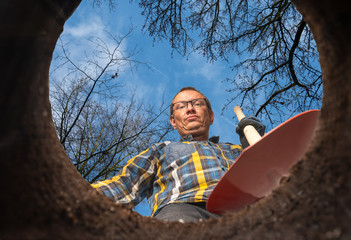 man with a shovel stands at a hole in the ground
