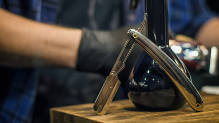 Obraz premium Danger razor close-up on the background of the hands of a barber