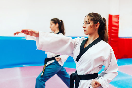 Two young women practice taekwondo in a training center