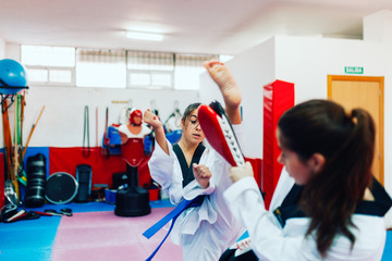 Two young women practice taekwondo in a training center
