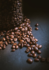 closeup of coffee beans on dark background and in a jar