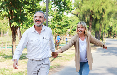 Caucasian elderly couple walking hand in hand in a park with love. concept of living a happy holiday