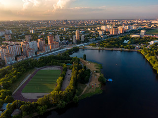 Fototapeta na wymiar Football stadium on the river in a residential area of the city, in the background houses and a highway. Aerial photography