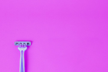 Disposable female razor on a purple background. A tool to remove hair from the skin. Female depilation and hygiene. Body care. Top view, copy space.