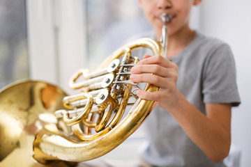 Caucasian boy learns to play horns, light window © natalialeb