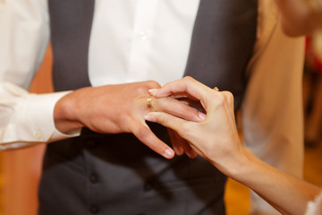 Obraz na płótnie Canvas bride puts on a wedding ring to the groom