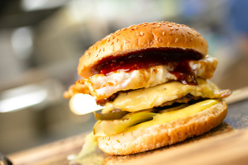 Close-up burger on the wood plate with fries on the blurred cafe background
