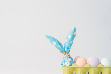 Easter background. Easter eggs painted with pastel colors on a light background next to an egg in a gift box resembling an Easter rabbit