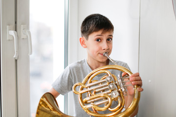 Caucasian boy learns to play horns, light window