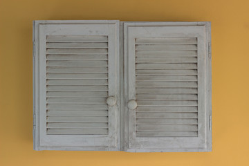 old white wooden cupboard on a yellow wall