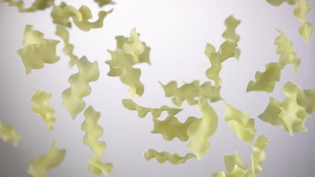 Pasta mafalde corte is flying up on a white background in slow motion