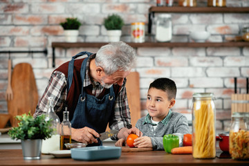 Grandpa and grandson in kitchen. Grandfather and his grandchild having fun while cooking.