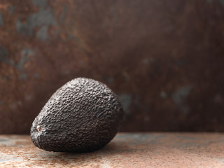 Whole ripe brown hass avocado fruit on dark table. Healthy fats. Side view, copy space