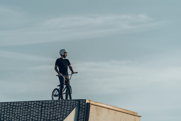 Bmx male rider looking away on top of stone bricks bike park