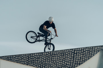 Bmx rider making a reversed wheelie on top of stone bricks bike park