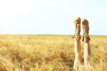 girl lies in the field with her legs up in boots / legs stick out in the field, the concept of...