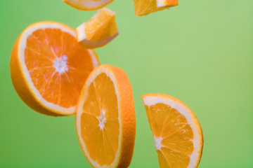 Green bright background and pieces of orange in air. Healthy and useful nutrition. Fruit and citrus. Vitamin C. Diet.